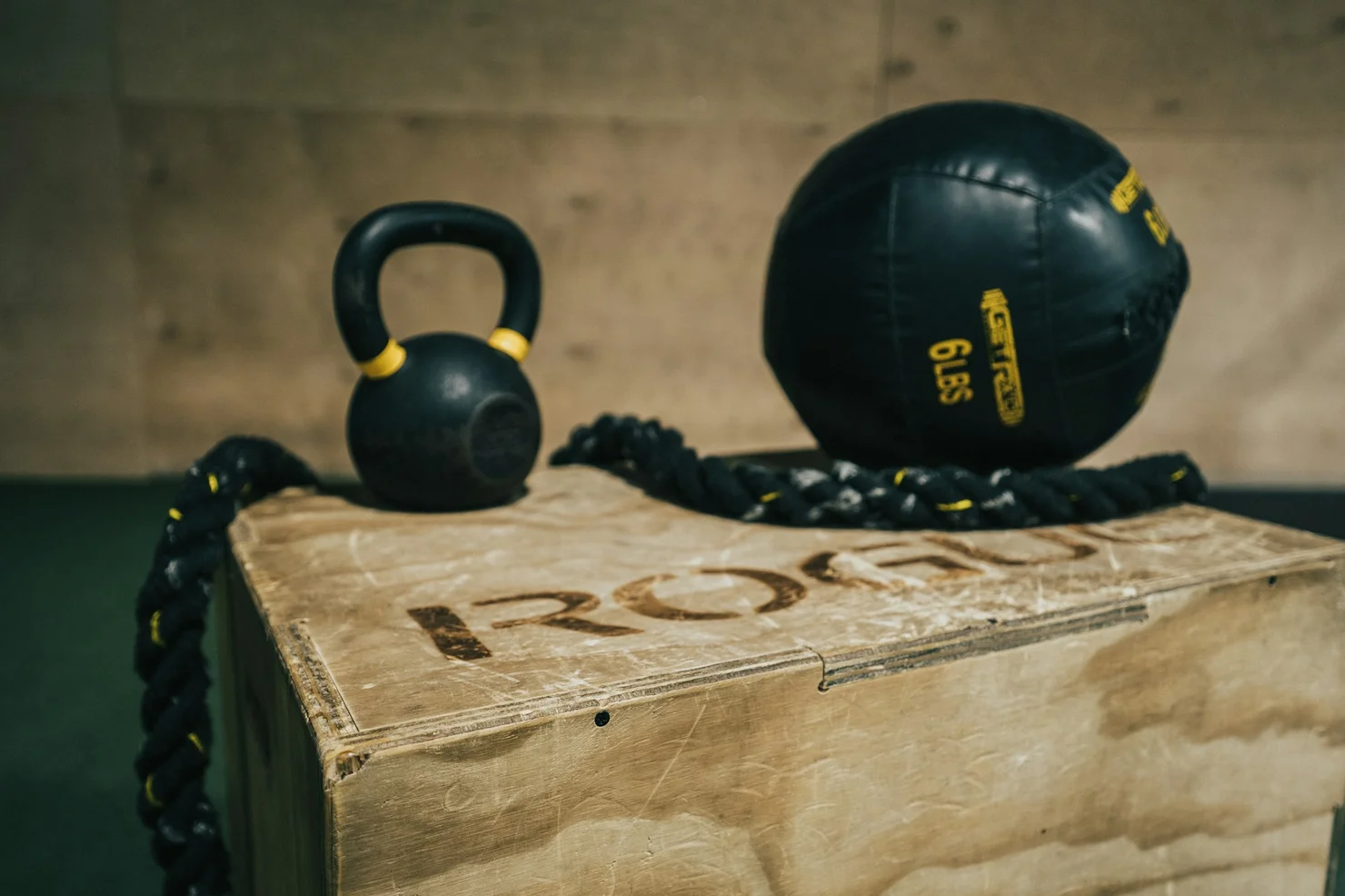 Eine CrossFit Holzbox, auf der eine Kettlebell und ein Medizinball liegen.