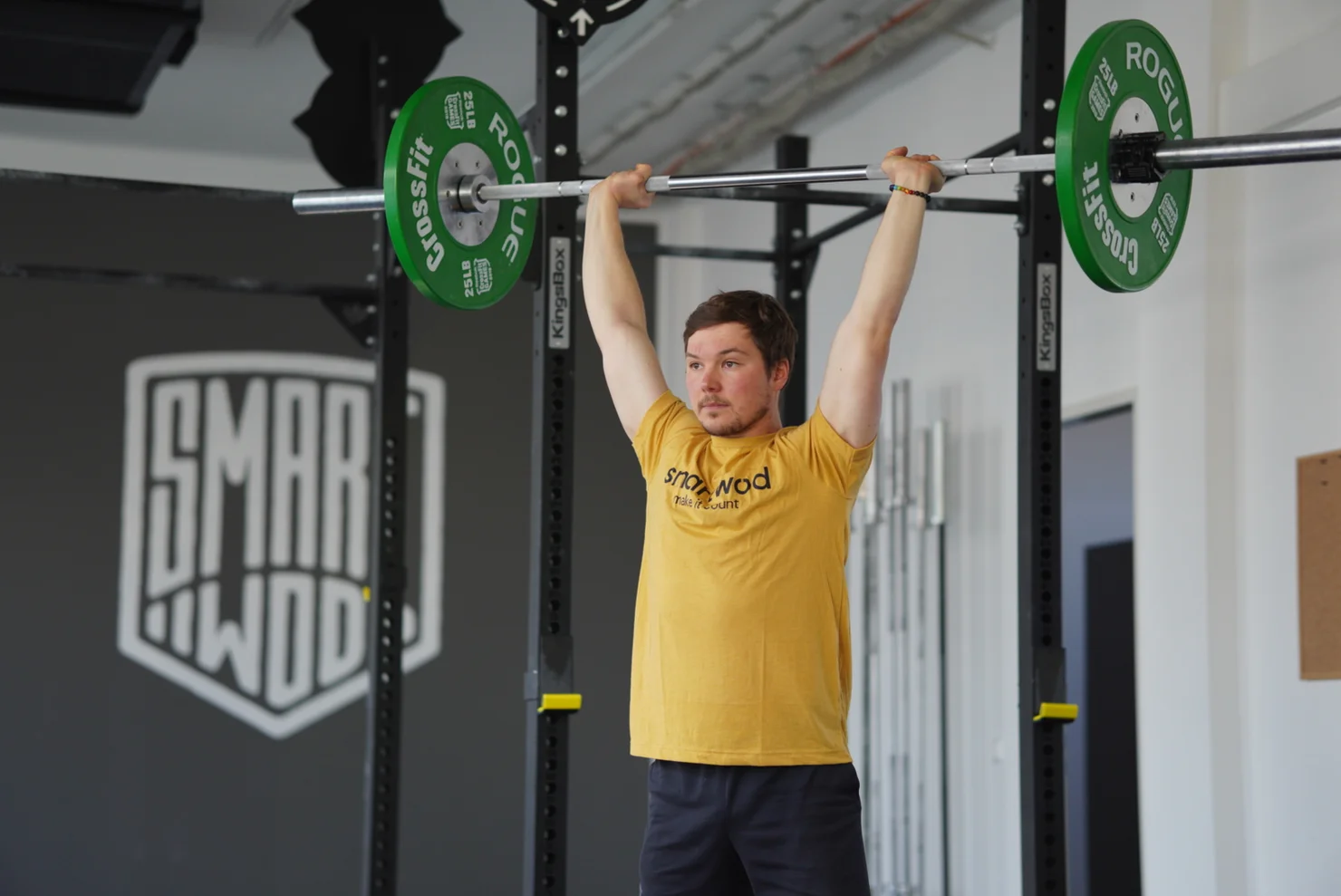 CrossFit Athlet, der eine Langhantel über Kopf hält.