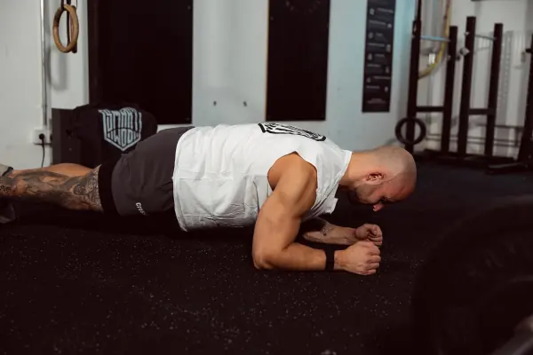 Athlete holding a forearm plank on the floor of a CrossFit box