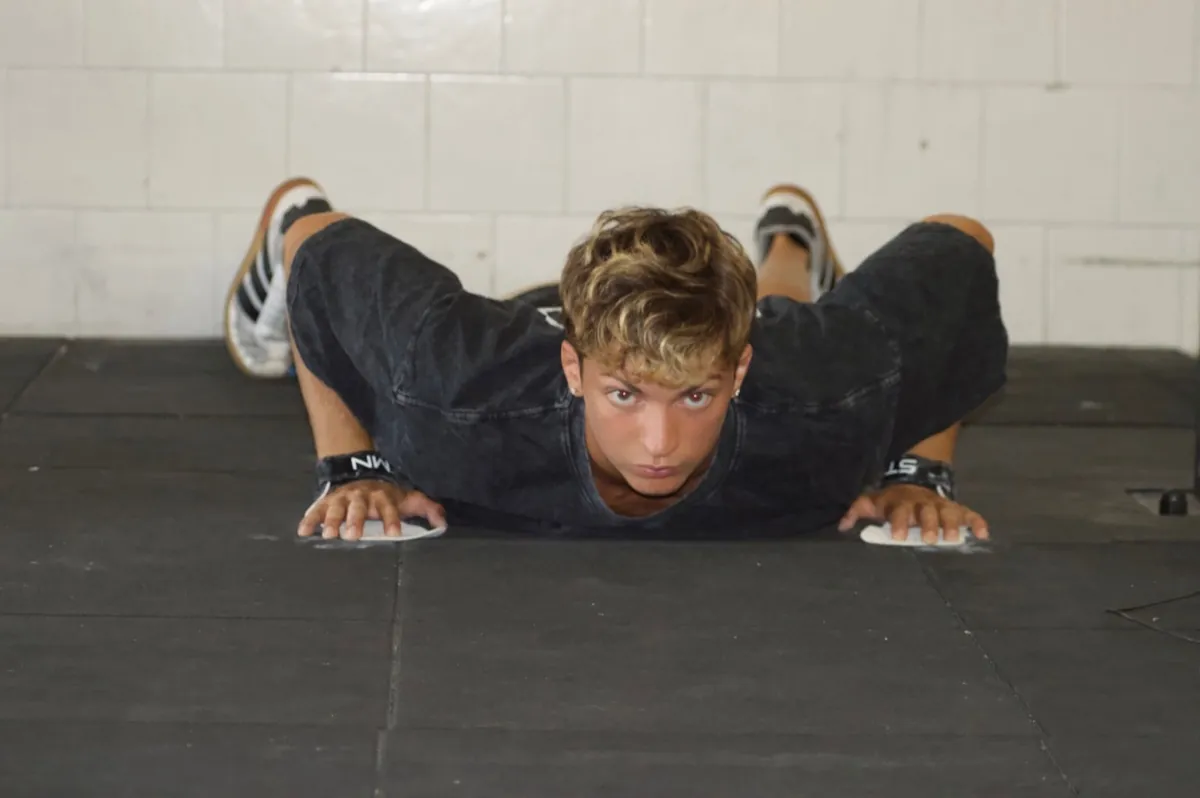Athlete in the bottom position of a push-up on paralettes