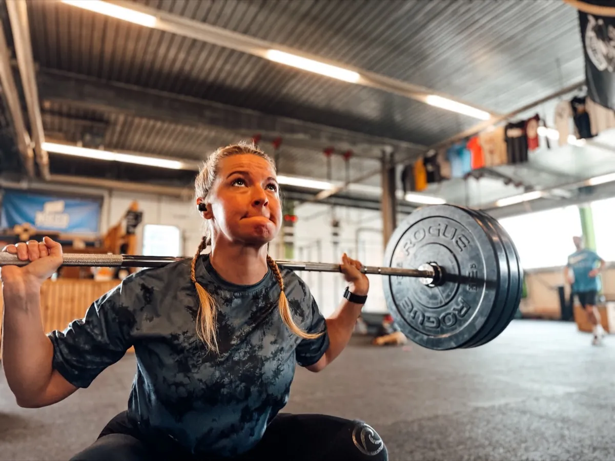 Athletin am tiefsten Punkt eines schweren Back Squats in einer CrossFit Box