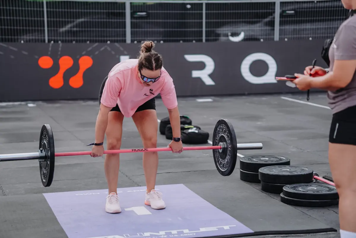 Athlete deadlifting on a competition floor while a judge records the reps