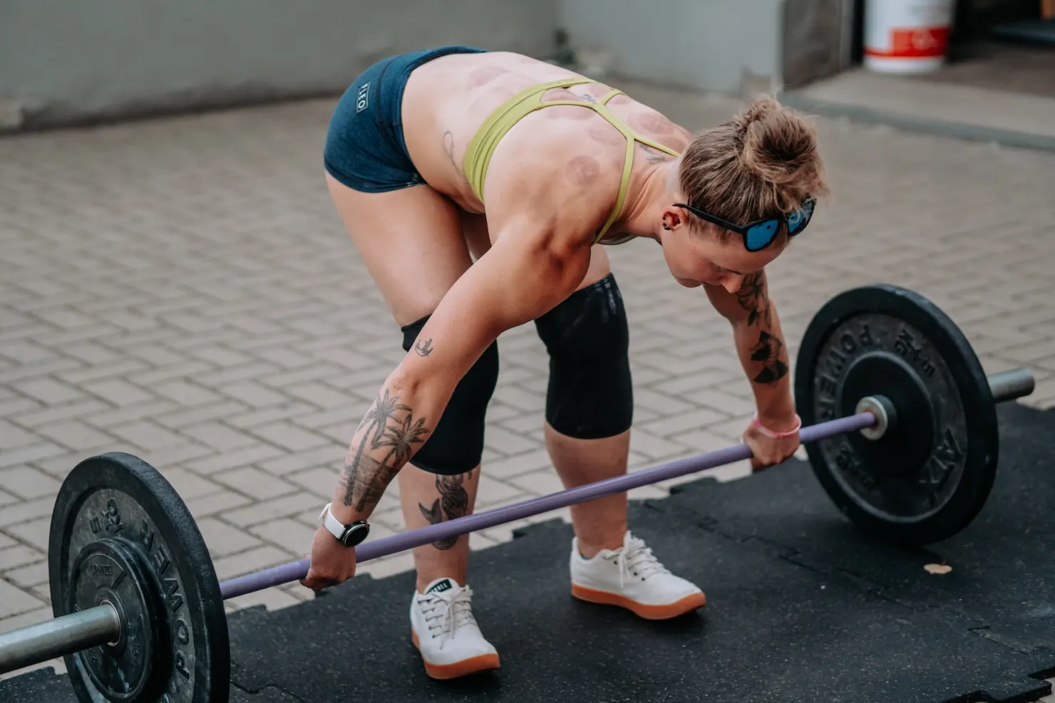 Athlete gripping the barbell to set up for a deadlift on an outdoor training area