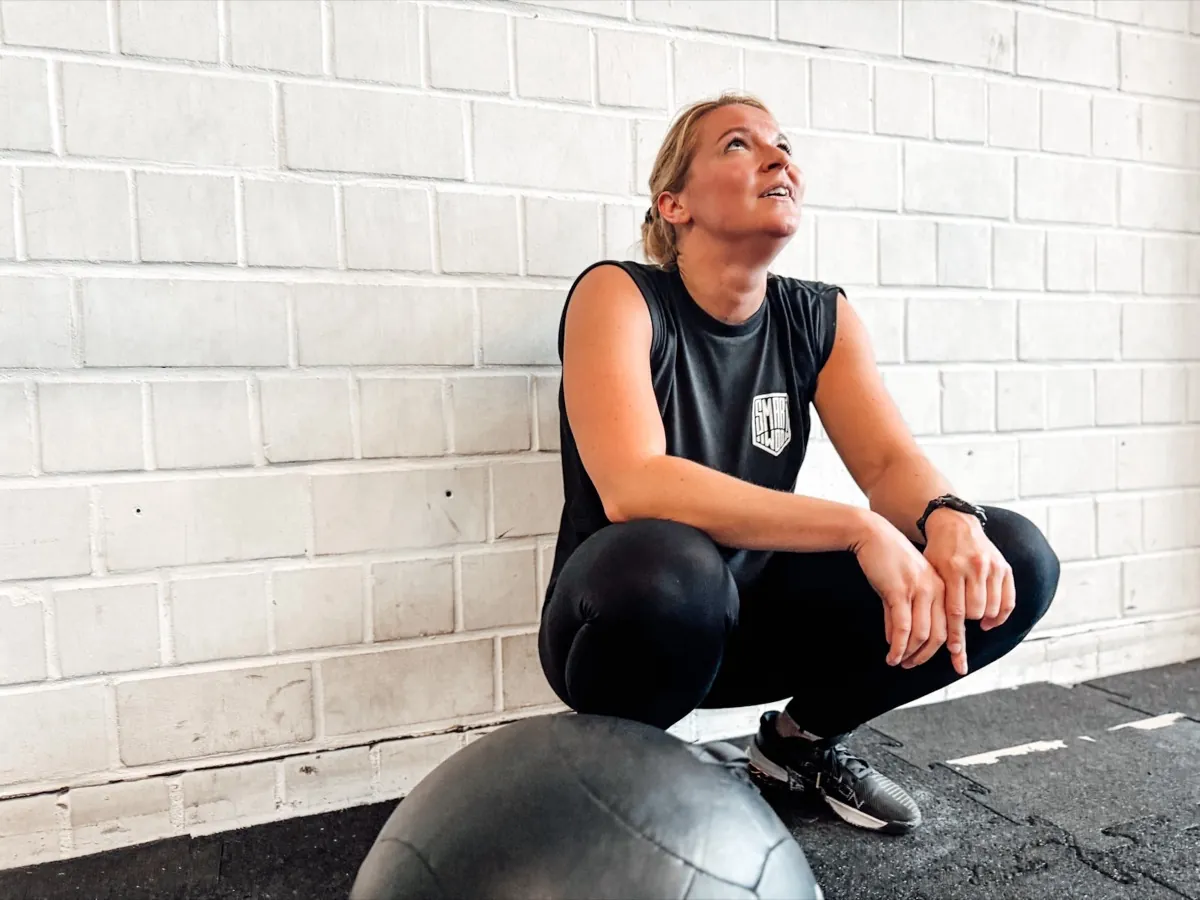 Athlete resting against the wall next to a medicine ball