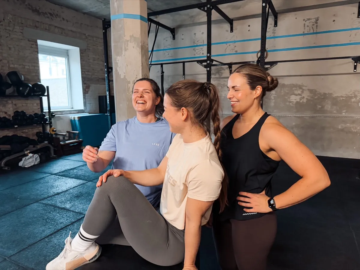 Three athletes laughing together during a training break in the gym