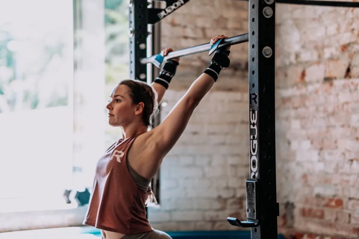 Athletin greift die Klimmzugstange am Rack
