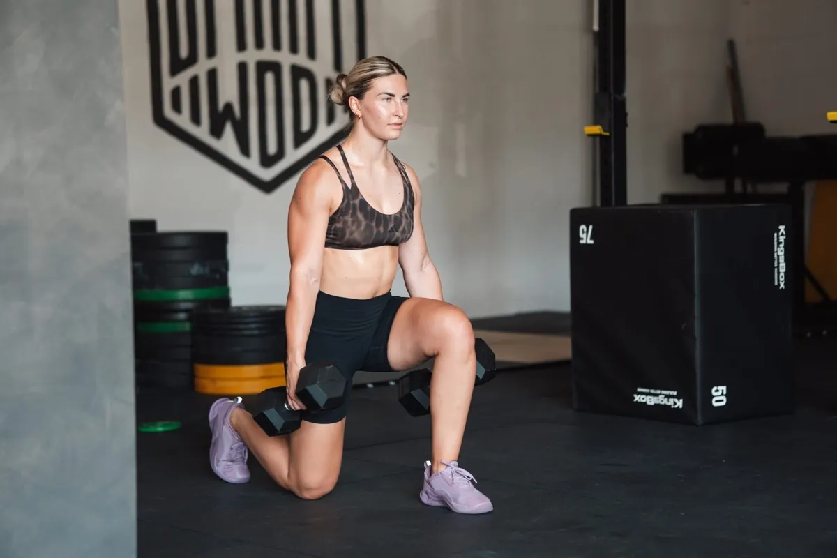 Athletin bei Lunges mit Kurzhanteln vor einer Plyo-Box