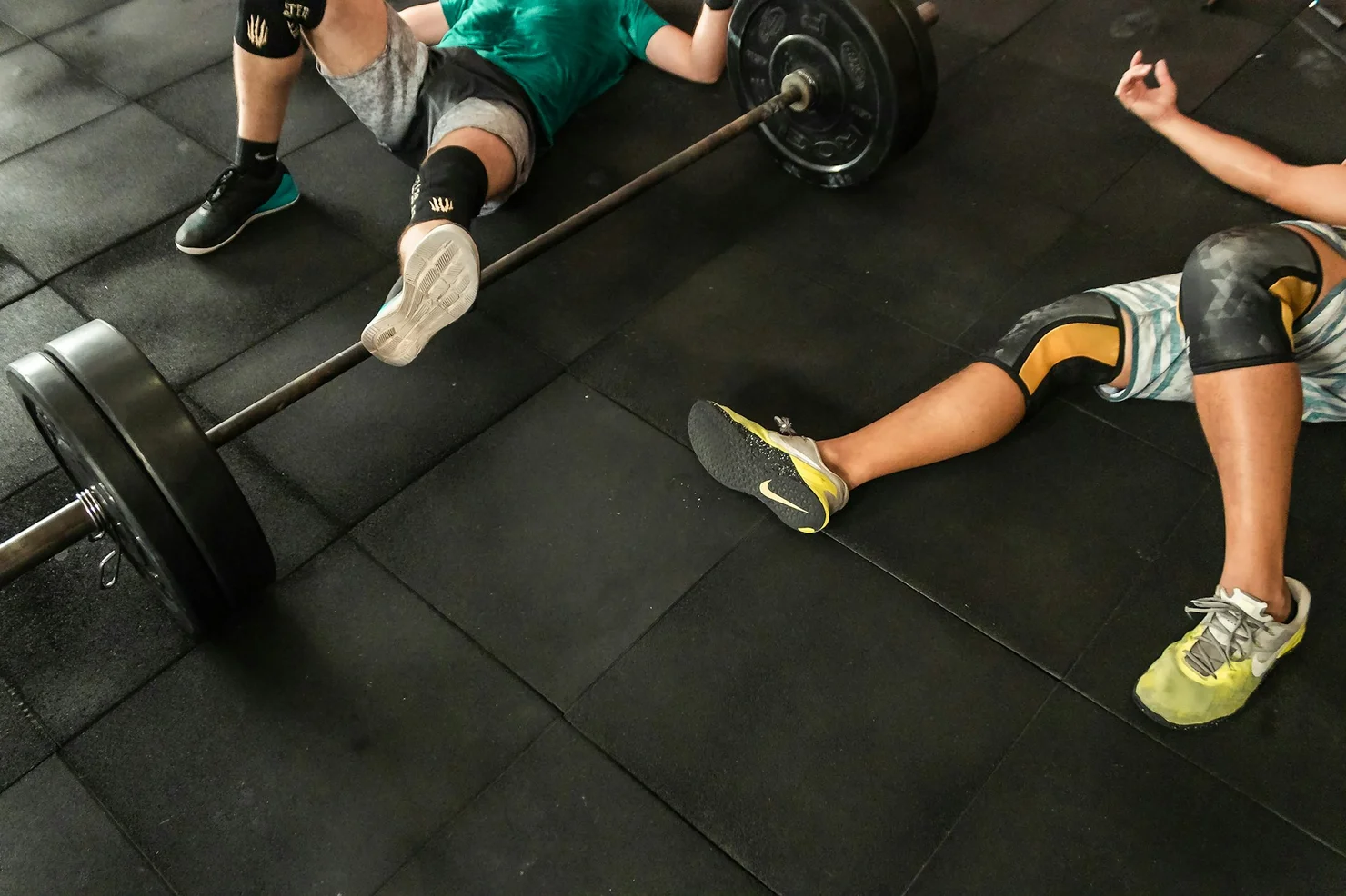 Zwei CrossFit Athleten, die nach dem Workout verschwitzt auf dem Boden liegen.