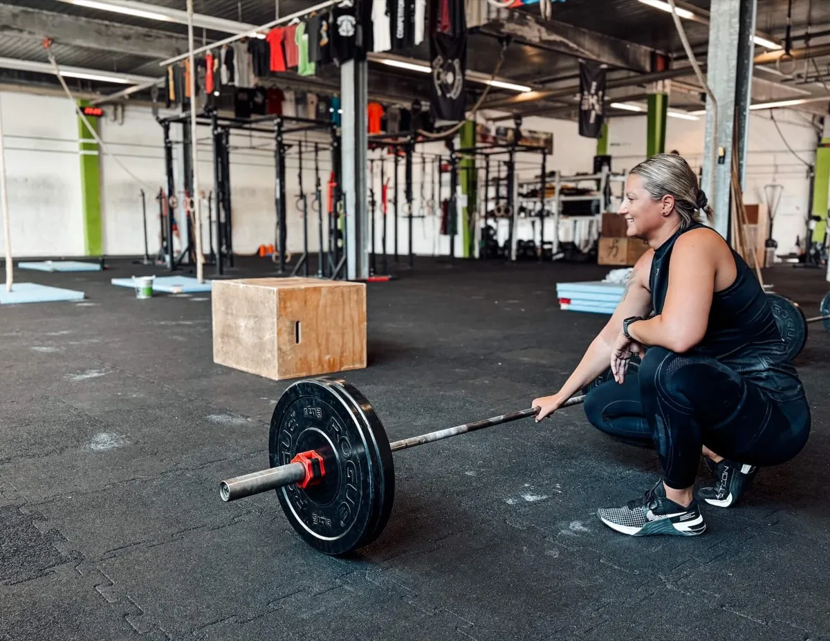 Athlete taking a short break next to the barbell in the gym