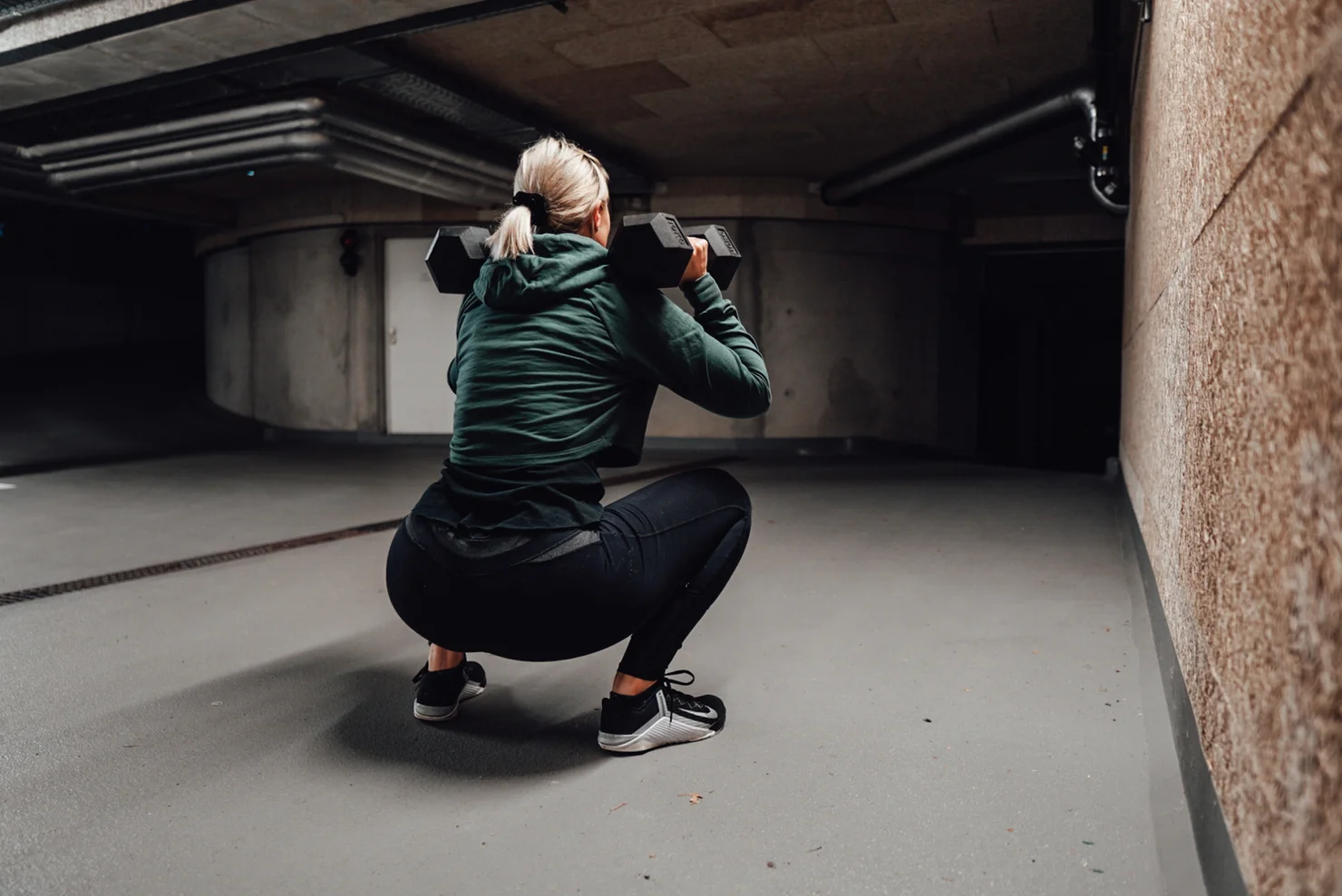 Frau, die mit zwei Kurzhanteln einen Squat macht